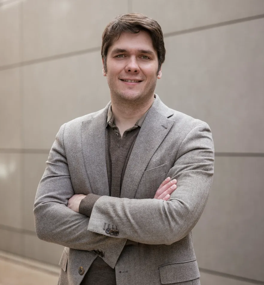 a man with his arms crossed standing in front of a building